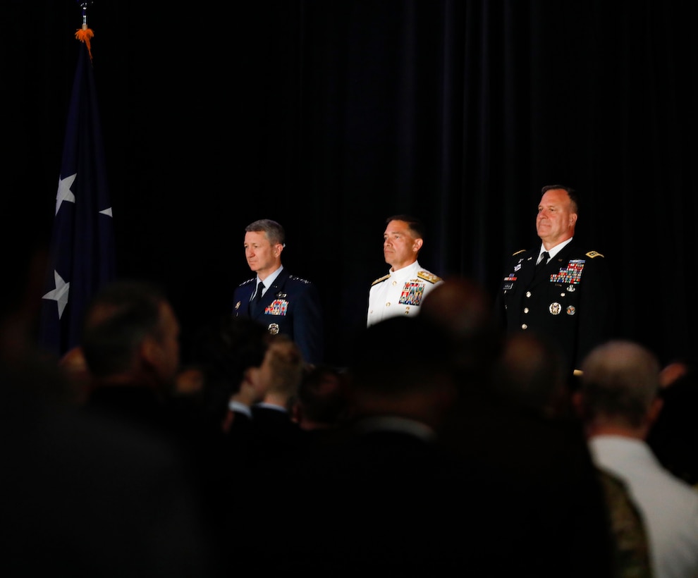 Chairman of the Joint Chiefs of Staff, U.S. Air Force Gen. Dan Caine, left, the incoming commander of U.S. Central Command (USCENTCOM), U.S. Navy Adm. Brad Cooper, center, and the outgoing commander of USCENTCOM, U.S. Army Gen. Michael Erik Kurilla, right, stand at attention at a change of command ceremony, 8 August 2025. Multiple Department of Defense officials attended the event as well as distinguished defense leaders from partner nations around the world. (U.S. Central Command Public Affairs photo by Tom Gagnier)