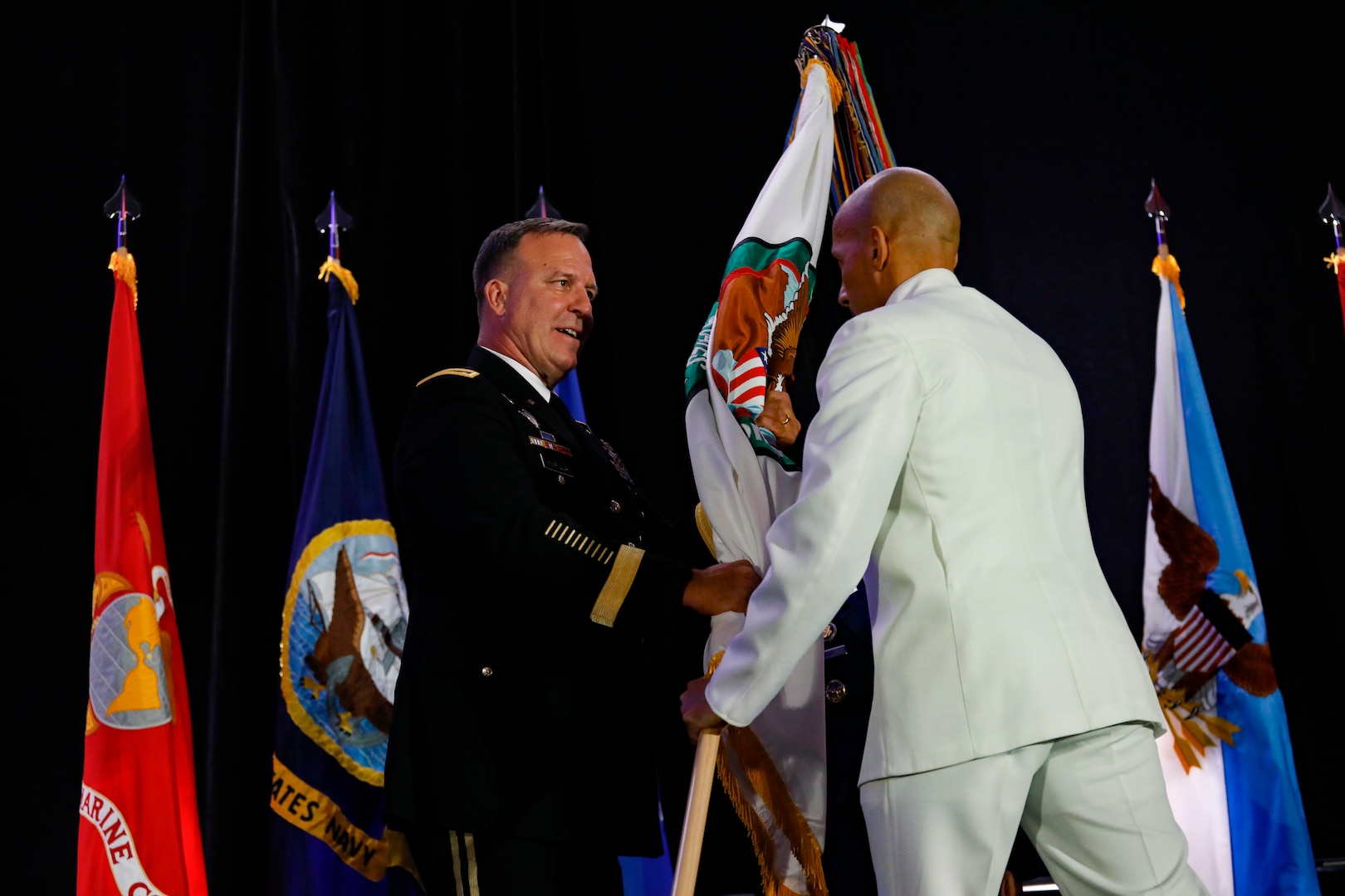 U.S. Central Command's (USCENTCOM) Senior Enlisted Leader, Fleet Master Chief Derrick Walters passes the USCENTCOM flag to the outgoing commander of USCENTCOM, U.S. Army Gen. Michael Erik Kurilla, during a change of command ceremony, 8 August 2025. Multiple Department of Defense officials attended the event as well as distinguished defense leaders from partner nations around the world. (U.S. Central Command Public Affairs photo by Tom Gagnier)