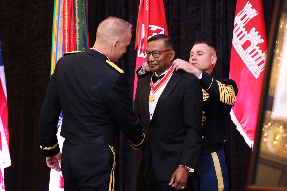 Lt. Gen. (Ret.) Thomas Bostick, the 53rd Chief of Engineer stands in a tuxedo between Lt. Gen. William H. "Butch" Graham, the 56 Chief of Engineers, and Command Sgt. Major Douglas Galick, the 15th Command Sgt. Major of the U.S. Army Corps of Engineers, as they present him with the Gold de Fleury Medal on his neck.