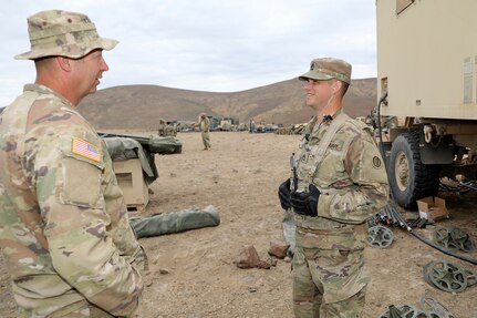 First Sgt. Nathan Brogan, left, Golf Company, 181st Brigade Support Battalion, Ephrata, Washington, talks with Sgt. 1st Class Jake Brand, right, 88 K, watercraft operator, and 92Y, Supply, Observer Coach/ Trainer, 1-364th Training Support Battalion, Joint Base Lewis McChord, during the Raven Focus exercise at Yakima Training Center, Washington, July 21, 2025.