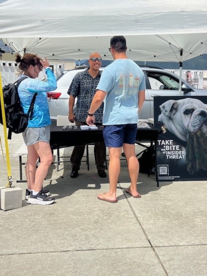 Analyst Joey Borgardt talks insider threat with visitors attending the MCB Hawaii airshow.
