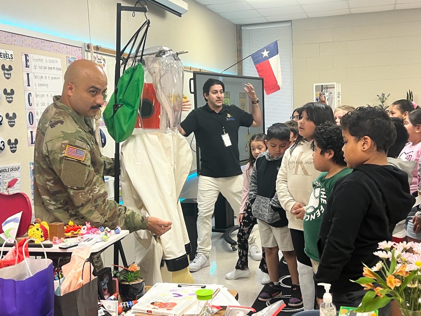 Capt. Jesus Silvas, a microbiologist with the U.S. Army Reserve Medical Command assigned to the 59th Medical Wing’s Office of Research and Technology Applications, shows students a Biosafety Level 4 Positive Pressure Suit Aug. 7, 2025, at Mendez Elementary School in San Marcos, Texas, as Dr. Israel Guerrero, a virologist with Texas Biomedical Research Institute, explains its use.
