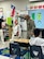 Capt. Jesus Silvas, a microbiologist with the U.S. Army Reserve Medical Command assigned to the 59th Medical Wing’s Office of Research and Technology Applications, shows students a Biosafety Level 4 Positive Pressure Suit Aug. 7, 2025, at Mendez Elementary School in San Marcos, Texas, as Dr. Israel Guerrero, a virologist with Texas Biomedical Research Institute, explains its use.