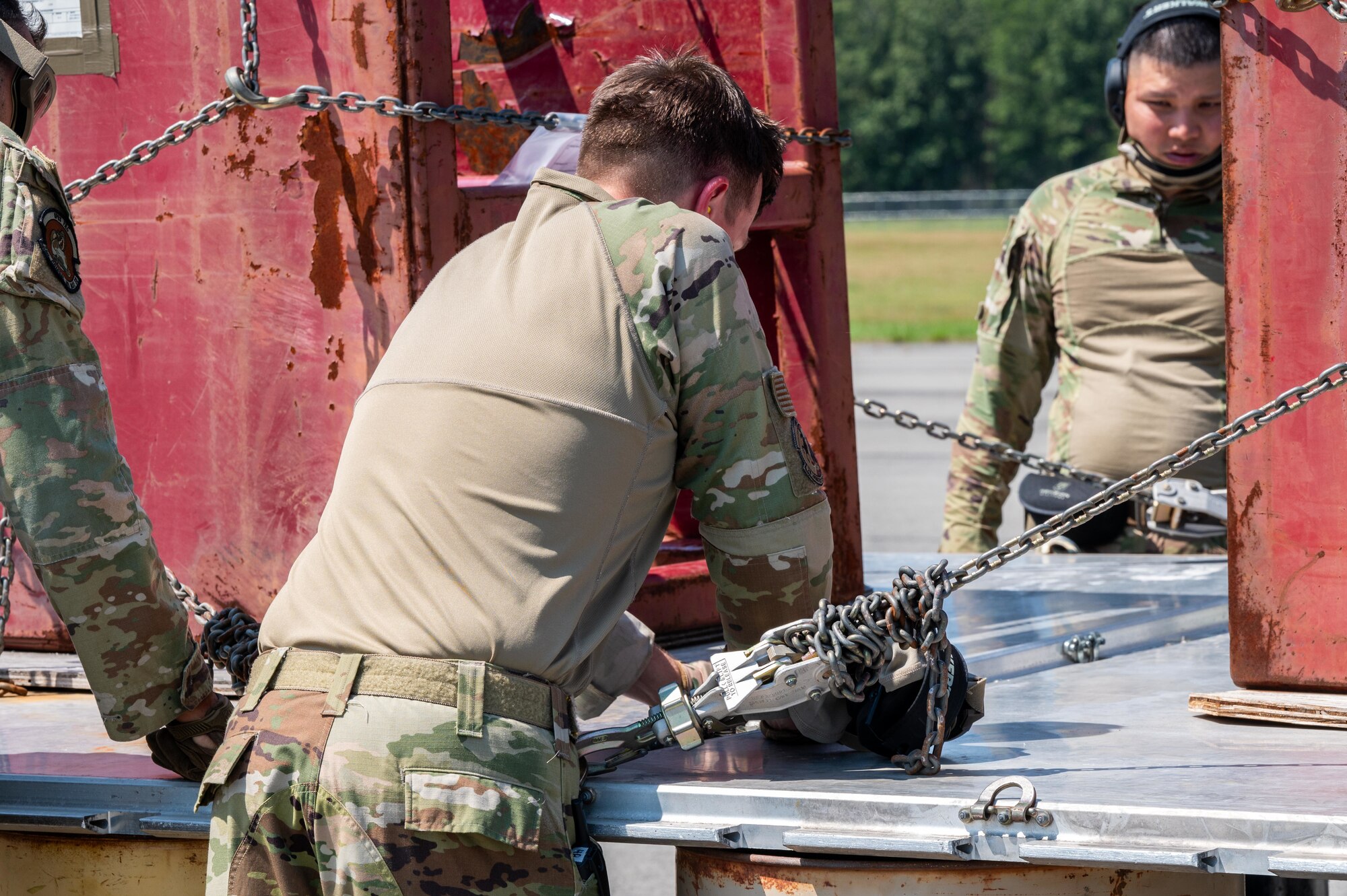 U.S. Air Force Tech. Sgt. Tylor Borggren, 21st Combat Air Base Squadron air logistics liaison, unchains cargo during exercise Bamboo Eagle 25-3 at Camp Robinson, Arkansas, August 4, 2025. The 21st ATF’s rapid force flow capability was demonstrated through integrated landing zone operations. (U.S. Air Force photo by Airman 1st Class Adrien Tran)