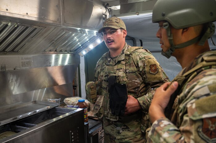 U.S. Air Force Staff Sgt. Chas Hunniford, 21st Combat Air Base Squadron fitness program manager, showcases an expandable single pallet expeditionary kitchen at a forward operating site during exercise Bamboo Eagle 25-3 at Camp Robinson, Arkansas, August 3, 2025. The ESPEK provides a fully functioning kitchen to support food service operations in forward-deployed environments. (U.S. Air Force photo by Airman 1st Class Adrien Tran)