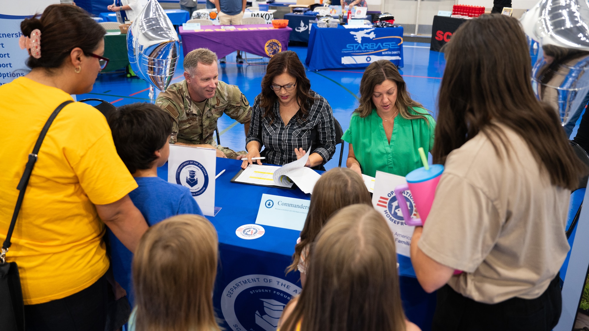 Military families are checked-in at a table during the Back-to-School Supplies Brigade.