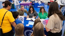 Military families are checked-in at a table during the Back-to-School Supplies Brigade.