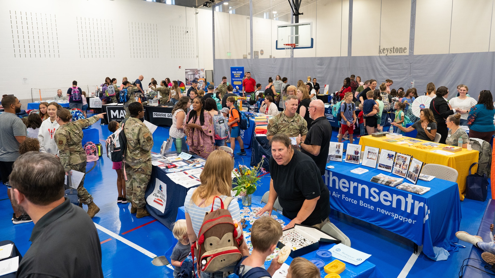 A wide shot of the Back-to-School Supplies Brigade event, showing military families interacting with sponsors.