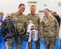 Three Airmen pose for a photo while holding backpacks.