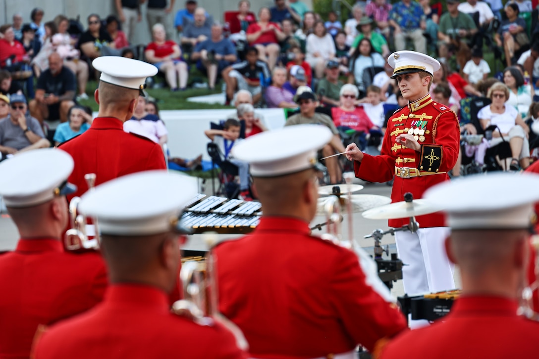 U.S. Marine Corps Capt. Courtney Lawrence, executive officer, "The Commandant's Own" United States Marine Drum & Bugle Corps conducts the band during a Battle Color Detachment performance at the National Museum of the Marine Corps in Quantico, Va., July 3, 2025. This performance was a part of the 2025 Summer Concert Series hosted by the Marine Corps Heritage Foundation. The guest of honor for this performance was Maj. Gen. James Lukeman (Ret.), president of the Marine Corps Heritage Foundation. (U.S. Marine Corps photo by Cpl. Christopher Prelle)