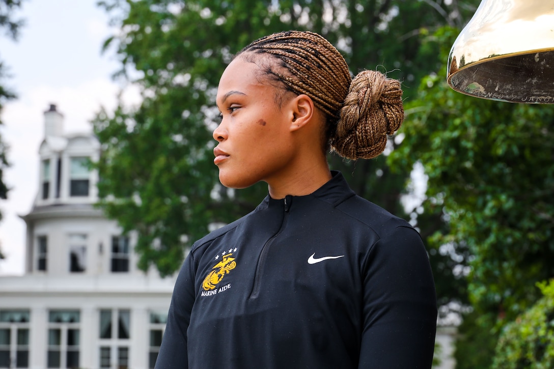 U.S. Marine Corps Cpl. Kevona Kelly, an intern with the Marine Corps Enlisted Aide Program at Marine Barracks Washington, poses in front of the ceremonial bell at Marine Barracks Washington, D.C., July 31, 2025. Kelly was selected as this week’s Motivator of the Week for consistently going above and beyond in and out of uniform. She has served as an intern in the program, training to become an enlisted aide to a general officer, for about six months. (U.S. Marine Corps photo by Cpl. Christopher Prelle)
