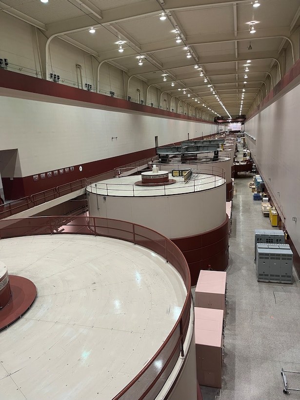 Image shows a row of circular structures that hold hydropower turbine units inside a powerhouse.