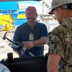 Pearl Harbor Naval Shipyard and Intermediate Maintenance Facility Commander Capt. Ryan D. McCrillis receives a briefing on drone capabilities from Naval Information Warfare Center technician June 18, 2025.