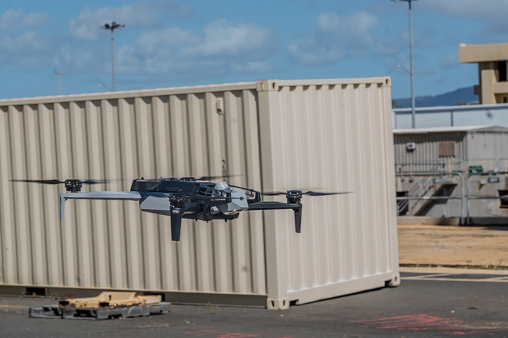 A Skydio X10D drone maneuvers near a shipping container during a demonstration at Pearl Harbor Naval Shipyard & Intermediate Maintenance Facility, Hawaii, June 18, 2025.
