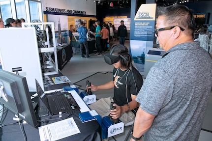 Jacob Eusebio, Crane & Transportation Operations Instructor/Performance Examiner with Pearl Harbor Naval Shipyard and Intermediate Maintenance Facility watches a Honolulu Community College CTE Academy student work with the mobile crane simulator during a community event at the Pacific Fleet Submarine Museum July 15, 2025.