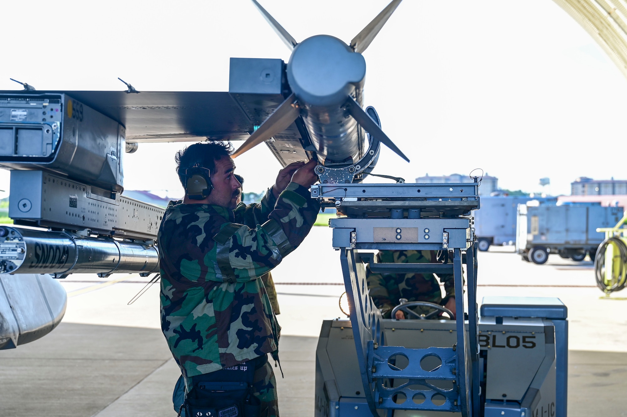 A man uses a tool on a munition.