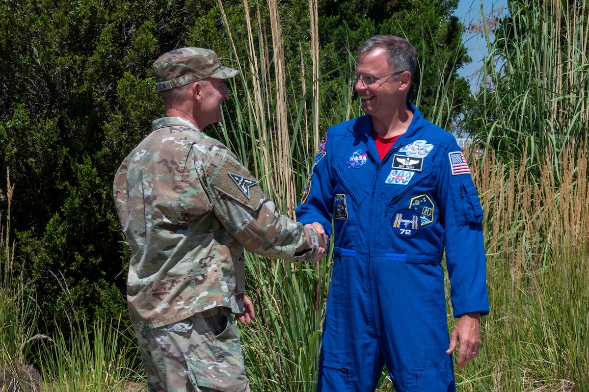 astronaut and military member shake hands