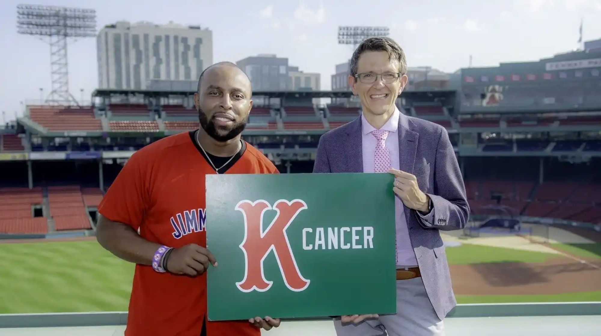 Two men stand near each other holding a sign.