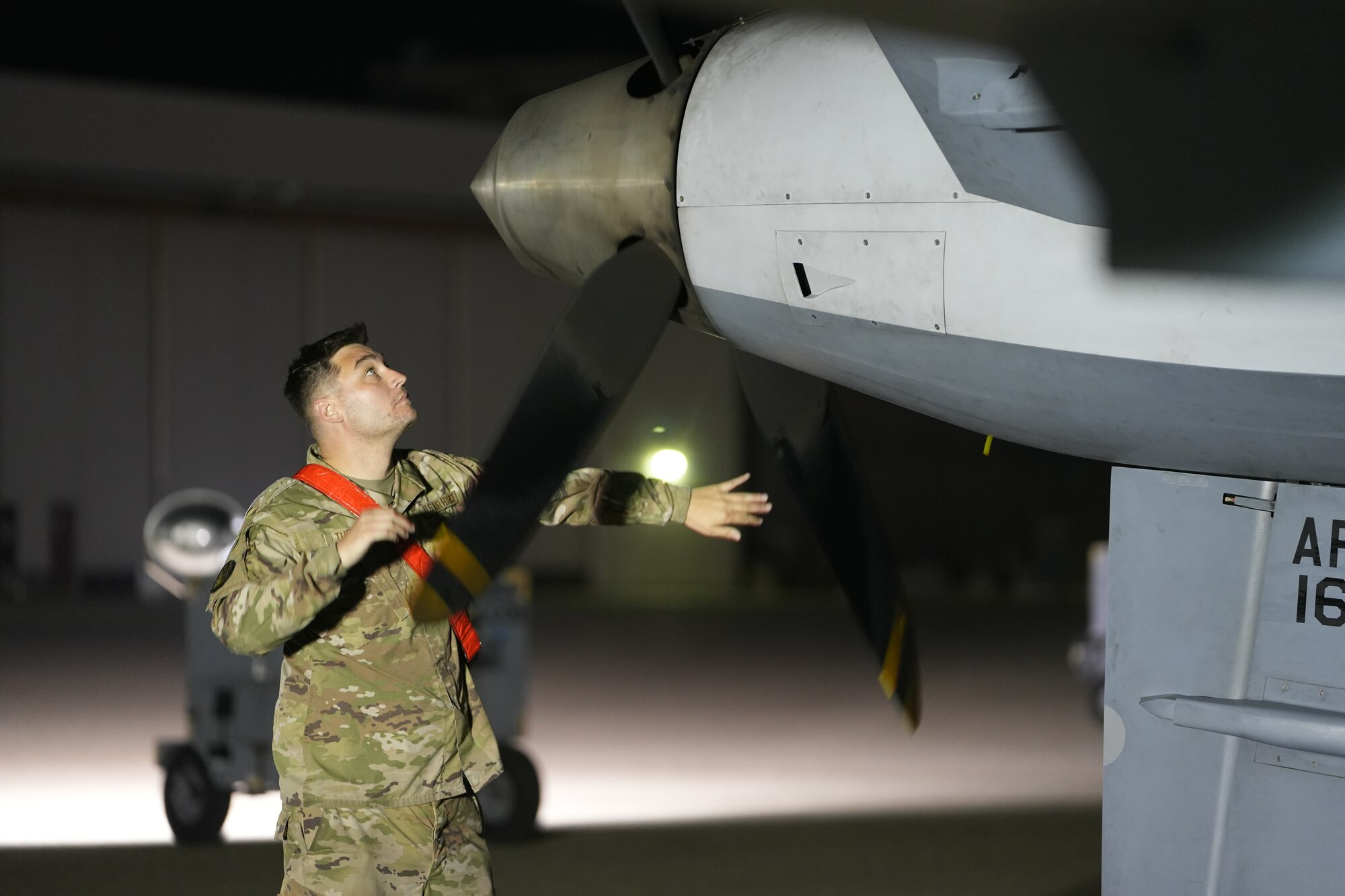 A man in a military uniform spins a propeller.