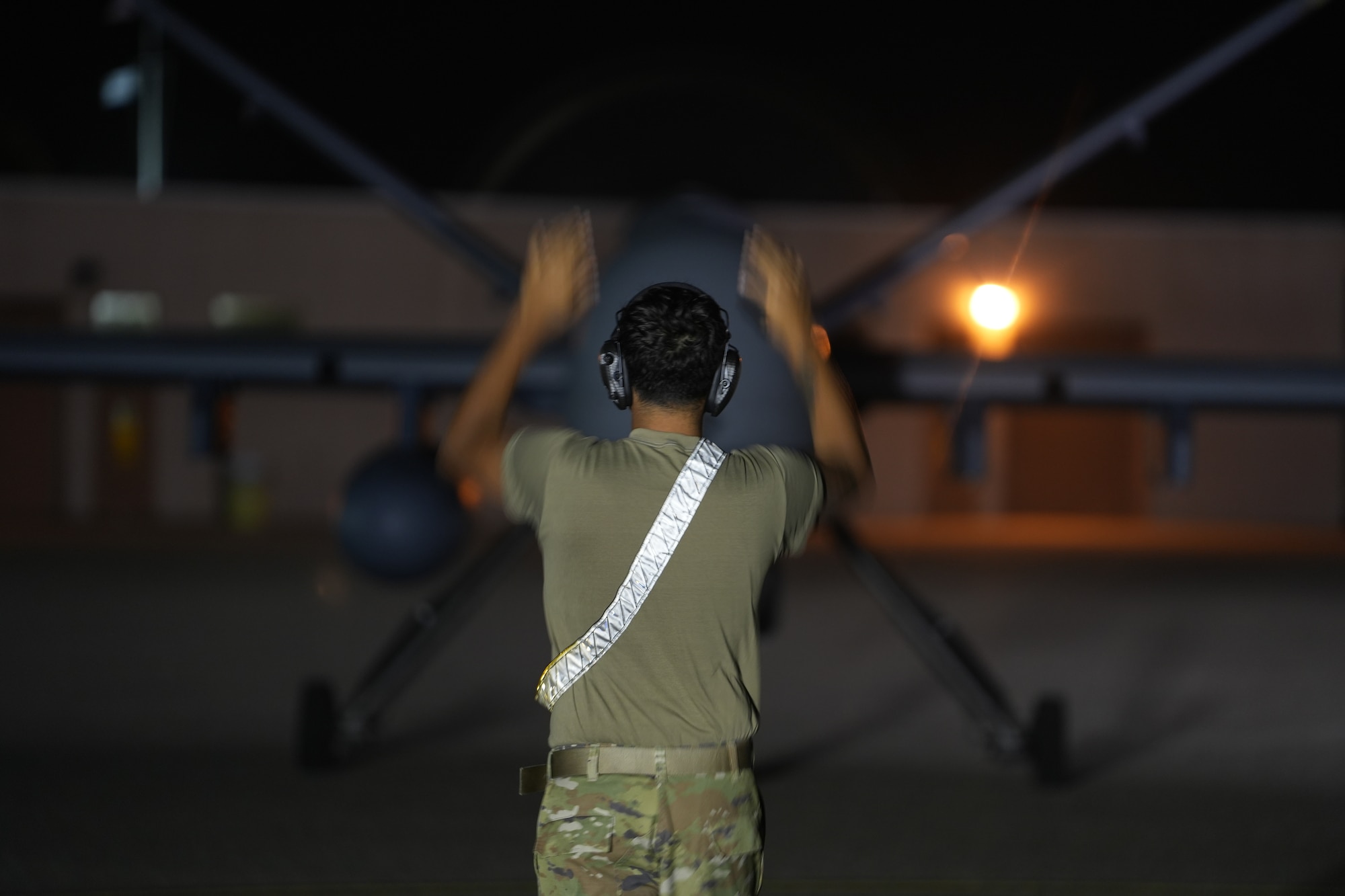 A man in a military uniform marshals an MQ-9 Reaper.