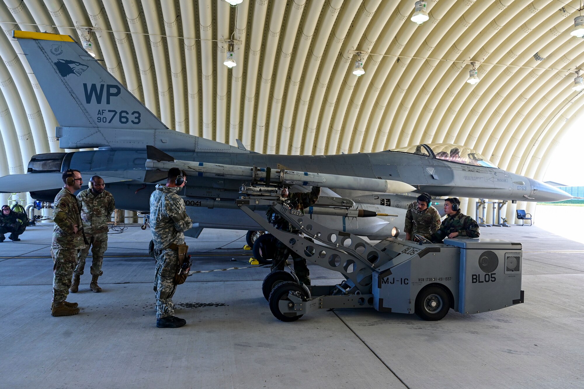 A grop of men stand around a jet.