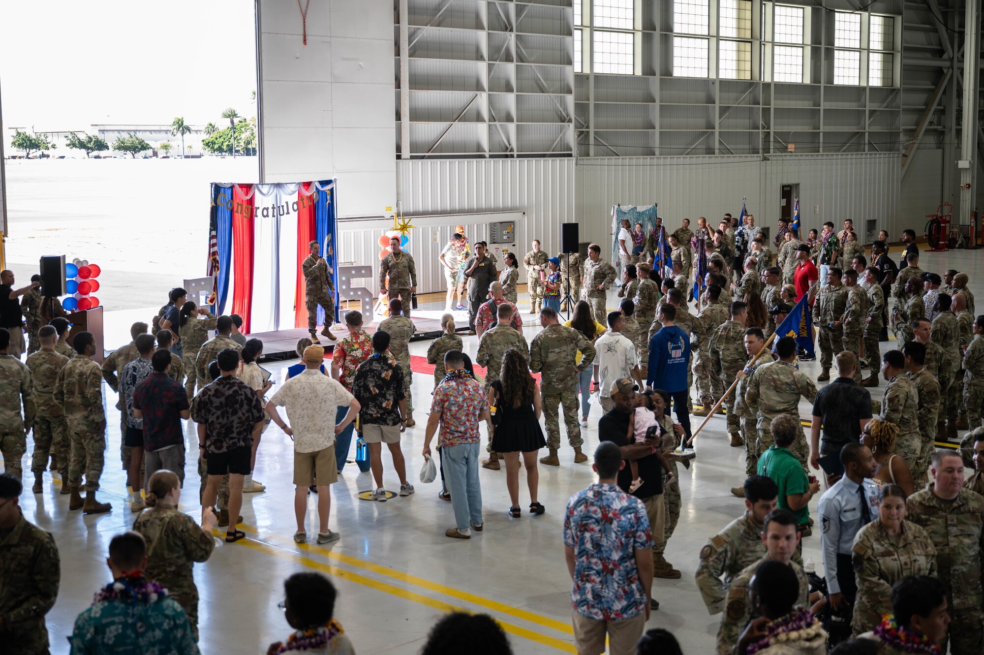 Airmen and civilians gathered together inside of a hangar for a celebration
