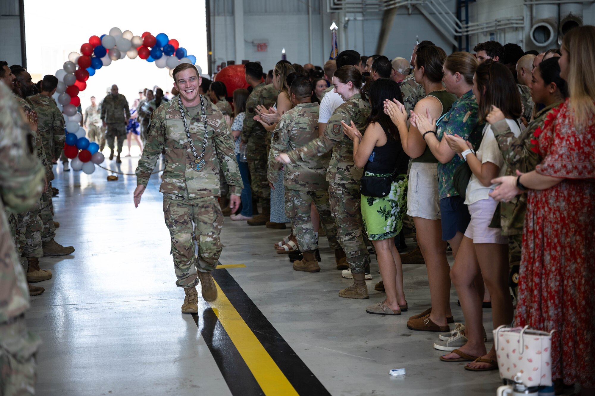 An Airman walking down an aisle of people during a celebration.
