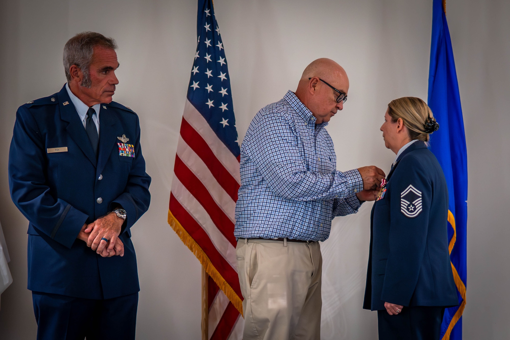 Senior Master Sgt. Spring Walden receives medal pinned on her dress blues by her husband during her retirement ceremony.
