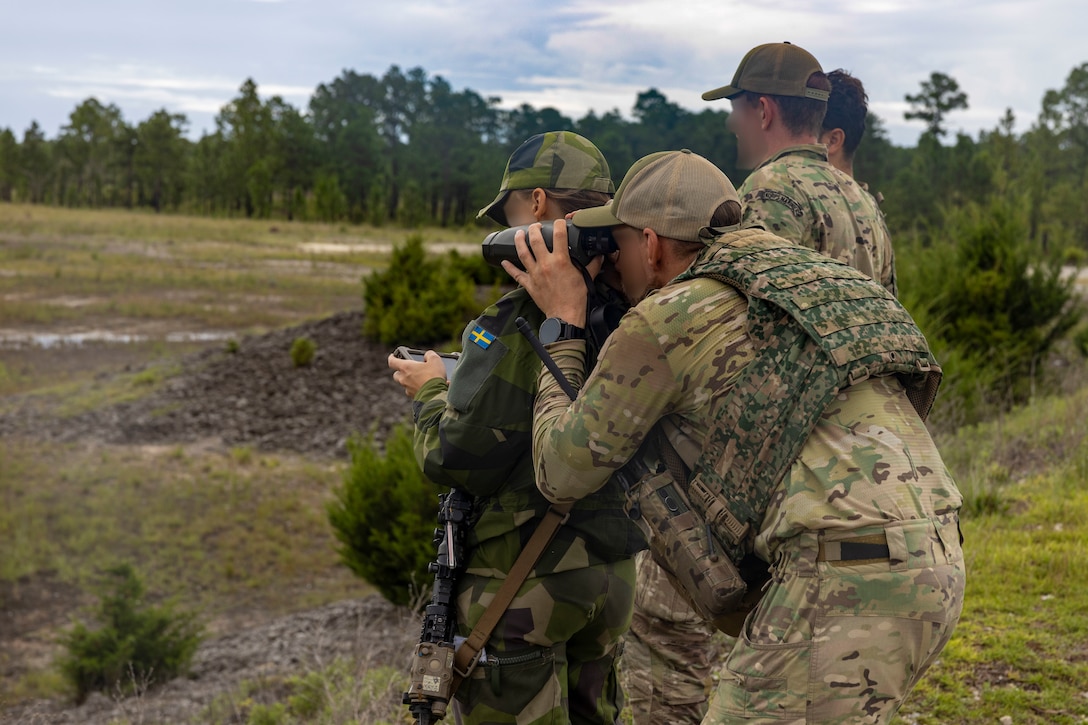 A Swedish armed forces member, left, and Dutch Marines with 25 RSTA Squadron, utilize an Android Tactical Assault Kit and binoculars to observe a training site during exercise Burmese Chase 25 at Marine Corps Base Camp Lejeune, North Carolina, Aug. 11, 2025. Burmese Chase is an annual U.S. led, multi-lateral training exercise comprised of integrating ground and air fires, infantry tactics and naval gunfire alongside NATO allies to enhance combat readiness and interoperability. (U.S. Marine Corps photo by Cpl. Marc Imprevert) (This photo has been altered for security purposes by blurring out faces.)