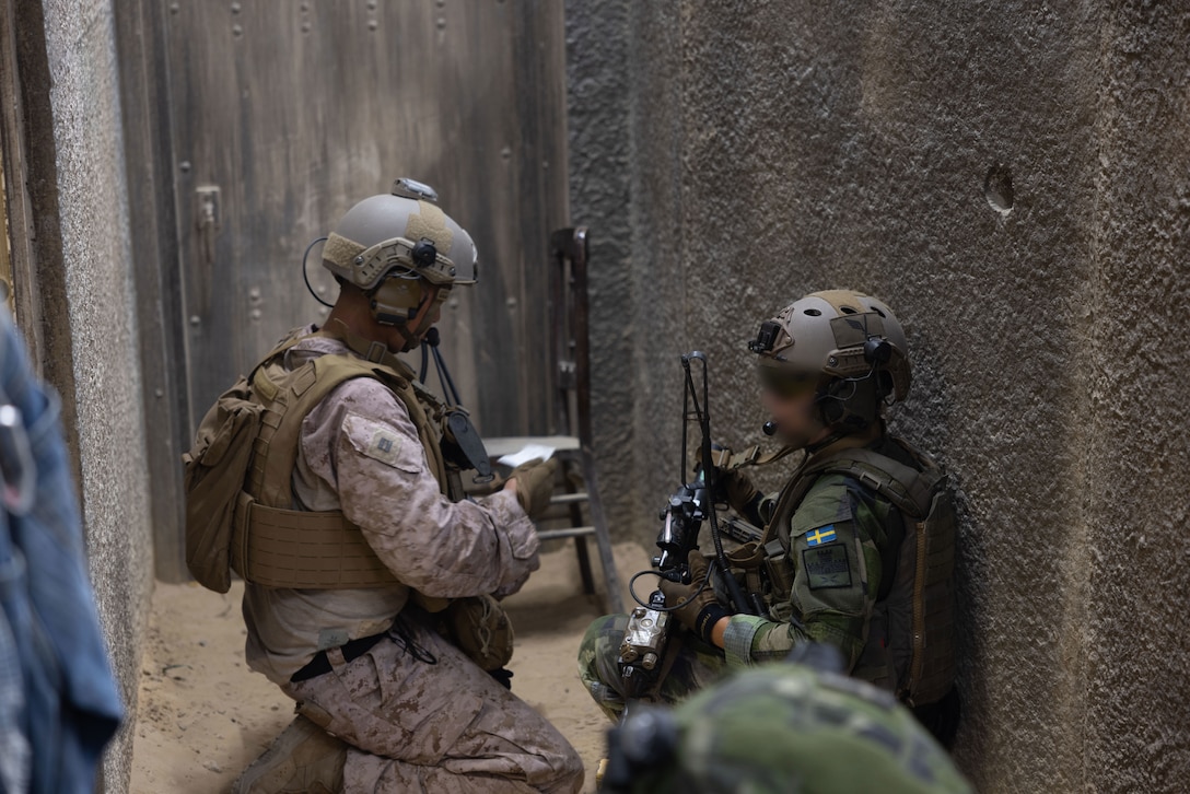 U.S. Marine Corps Capt. David Min, left, an air officer with 2nd Air Naval Gunfire Liaison Company, II Marine Expeditionary Force Information Group, and a Swedish armed forces member discuss the plan of action during exercise Burmese Chase 25 at Marine Corps Base Camp Lejeune, North Carolina, Aug. 8, 2025. Burmese Chase is an annual U.S. led, multi-lateral training exercise comprised of integrating ground and air fires, infantry tactics and naval gunfire alongside NATO allies to enhance combat readiness and interoperability. (U.S. Marine Corps photo by LCpl. Weston Lindstrom) (This photo has been altered for security purposes by blurring out faces.)