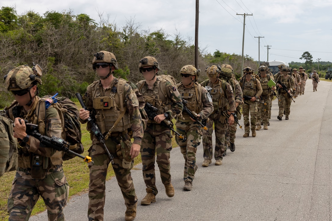 U.S. Marines with 2nd Air Naval Gunfire Liaison Company, II Marine Expeditionary Force Information Group, and NATO allies hike to their objective during exercise Burmese Chase 25 at Marine Corps Auxiliary Landing Field Bogue, North Carolina, Aug. 7, 2025. Burmese Chase is an annual U.S. led, multi-lateral training exercise comprised of integrating ground and air fires, infantry tactics and naval gunfire alongside NATO allies to enhance combat readiness and interoperability. (U.S. Marine Corps photo by Cpl. Marc Imprevert) (This photo has been altered for security purposes by blurring out faces.)