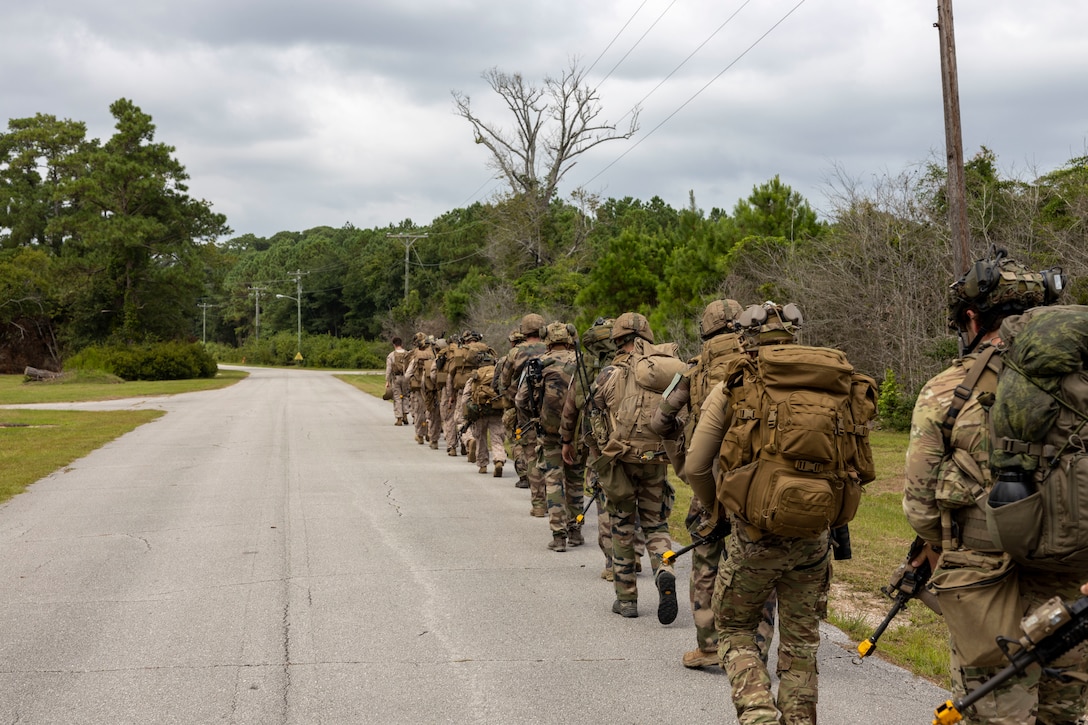 U.S. Marines with 2nd Air Naval Gunfire Liaison Company, II Marine Expeditionary Force Information Group, and NATO allies hike to their objective during exercise Burmese Chase 25 at Marine Corps Auxiliary Landing Field Bogue, North Carolina, Aug. 7, 2025. Burmese Chase is an annual U.S. led, multi-lateral training exercise comprised of integrating ground and air fires, infantry tactics and naval gunfire alongside NATO allies to enhance combat readiness and interoperability. (U.S. Marine Corps photo by Cpl. Marc Imprevert)
