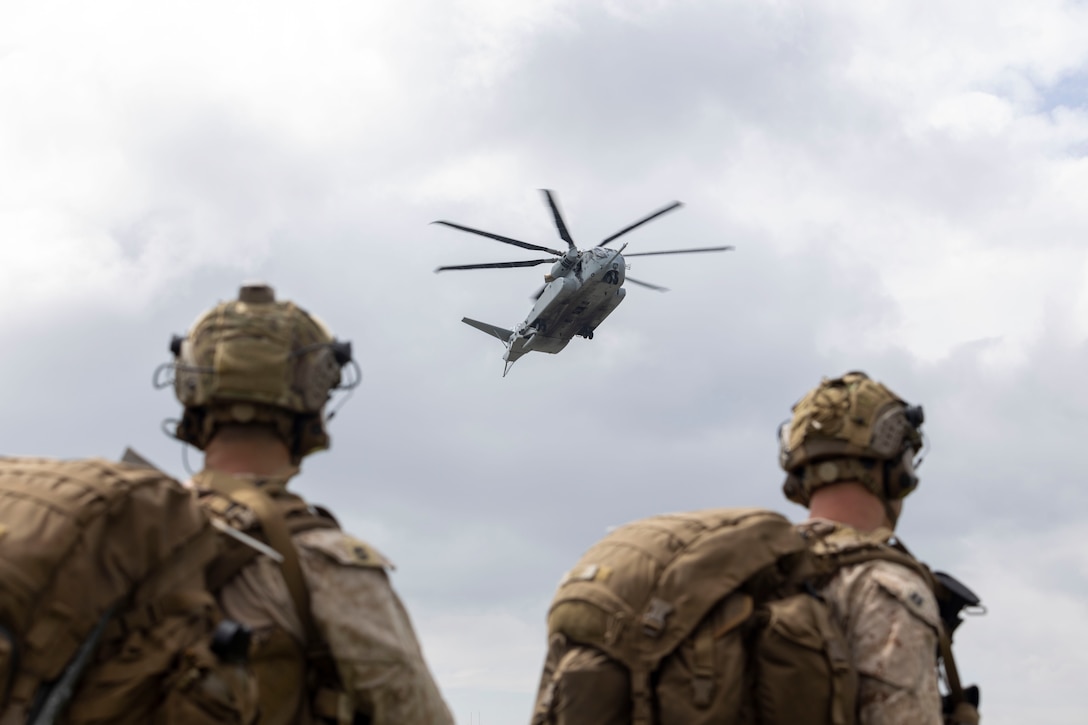 U.S. Marines with 2nd Air Naval Gunfire Liaison Company, II Marine Expeditionary Force Information Group, observe a CH-53E Super Stallion with Marine Heavy Helicopter Squadron 461, Marine Aircraft Group 29, 2nd Marine Aircraft Wing, landing during exercise Burmese Chase 25 at Marine Corps Auxiliary Landing Field Bogue, North Carolina, Aug. 7, 2025. Burmese Chase is an annual U.S. led, multi-lateral training exercise comprised of integrating ground and air fires, infantry tactics and naval gunfire alongside NATO allies to enhance combat readiness and interoperability. (U.S. Marine Corps photo by Cpl. Marc Imprevert)