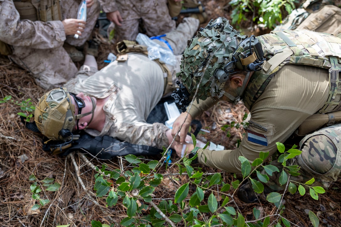 A U.S. Marine with 2nd Air Naval Gunfire Liaison Company, II Marine Expeditionary Force Information Group, receives simulated medical care from a Dutch Marine with 25 RSTA Squadron during a casualty evacuation drill as part of exercise Burmese Chase 25 at Marine Corps Base Camp Lejeune, North Carolina, Aug. 7, 2025. Burmese Chase is an annual U.S. led, multi-lateral training exercise comprised of integrating ground and air fires, infantry tactics and naval gunfire alongside NATO allies to enhance combat readiness and interoperability. (U.S. Marine Corps photo by Cpl. Marc Imprevert)