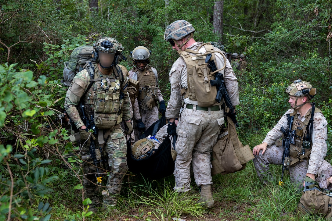 U.S. Marines and Sailors with 2nd Air Naval Gunfire Liaison Company, II Marine Expeditionary Force Information Group, and Dutch Marines with 25 RSTA Squadron, transport a simulated casualty during a casualty evacuation drill as part of exercise Burmese Chase 25 at Marine Corps Base Camp Lejeune, North Carolina, Aug. 7, 2025. Burmese Chase is an annual U.S. led, multi-lateral training exercise comprised of integrating ground and air fires, infantry tactics and naval gunfire alongside NATO allies to enhance combat readiness and interoperability. (U.S. Marine Corps photo by Cpl. Marc Imprevert)  (This photo has been altered for security purposes by blurring out faces.)