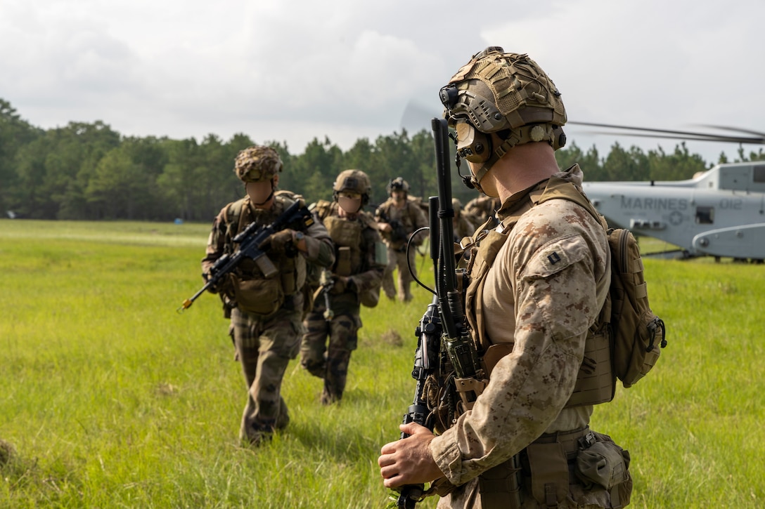 U.S. Marine Corps Capt. Karl Skerry, a fire support officer with 2nd Air Naval Gunfire Liaison Company, II Marine Expeditionary Force Information Group, directs NATO allies to their objective point during a casualty evacuation drill as part of exercise Burmese Chase 25 at Marine Corps Base Camp Lejeune, North Carolina, Aug. 7, 2025. Burmese Chase is an annual U.S. led, multi-lateral training exercise comprised of integrating ground and air fires, infantry tactics and naval gunfire alongside NATO allies to enhance combat readiness and interoperability. (U.S. Marine Corps photo by Cpl. Marc Imprevert) (This photo has been altered for security purposes by blurring out faces.)
