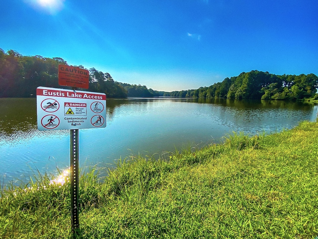 A sign in front of a small lake