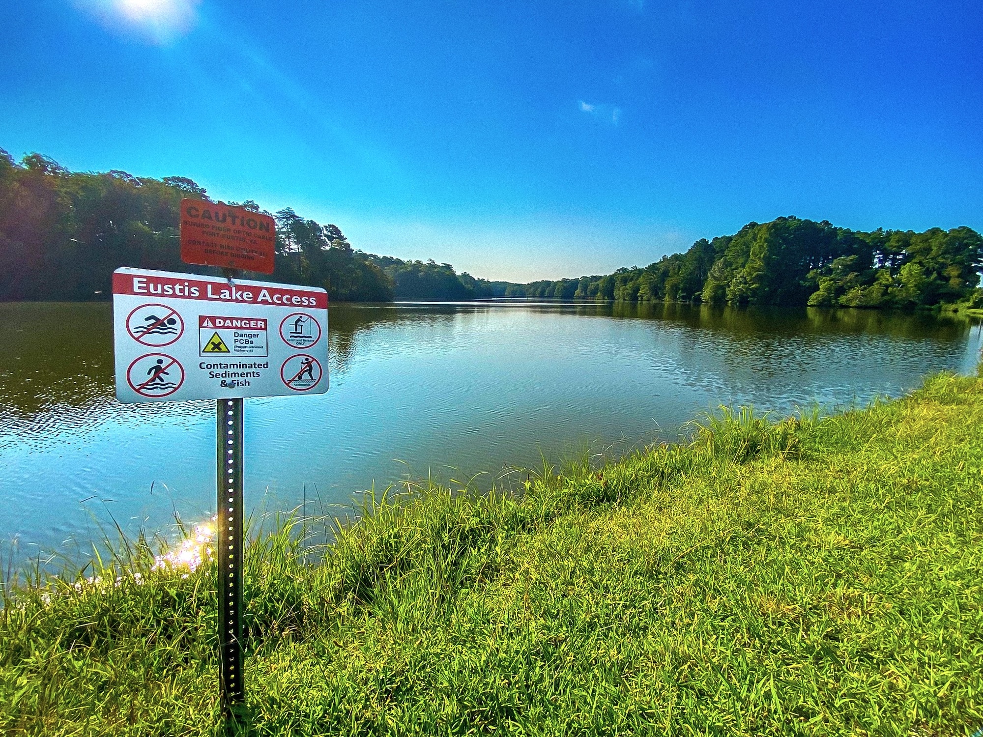 A sign in front of a small lake