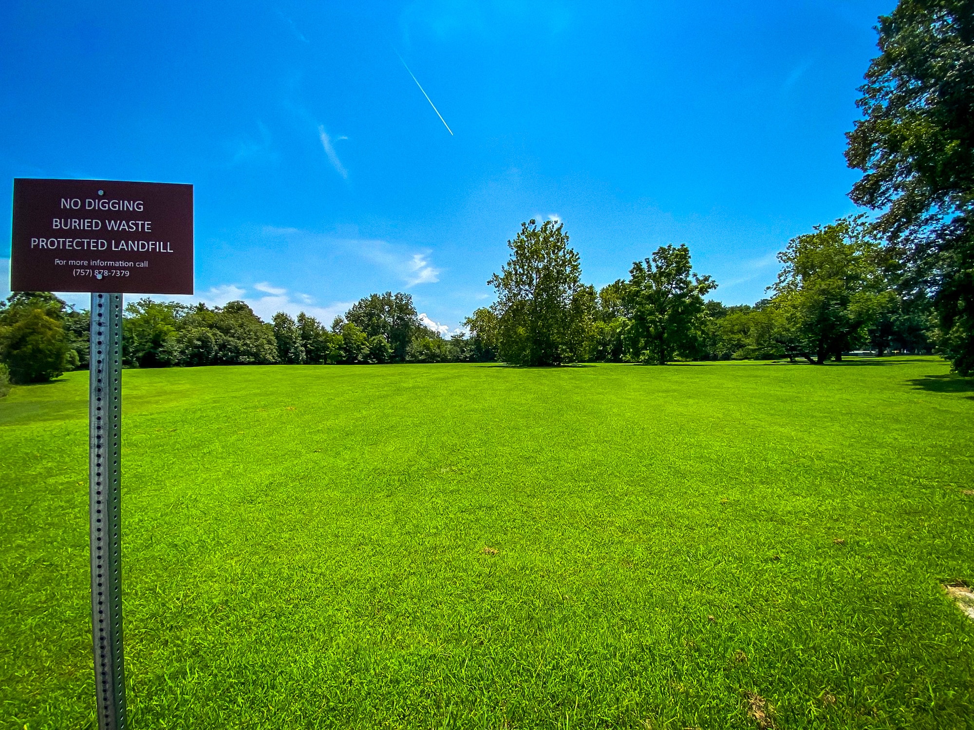 A sign in front of a grassy field