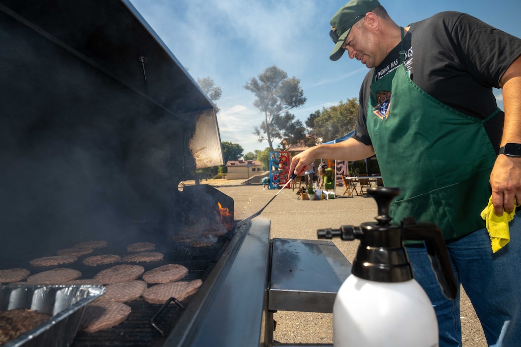 man grills burgers on a large grill