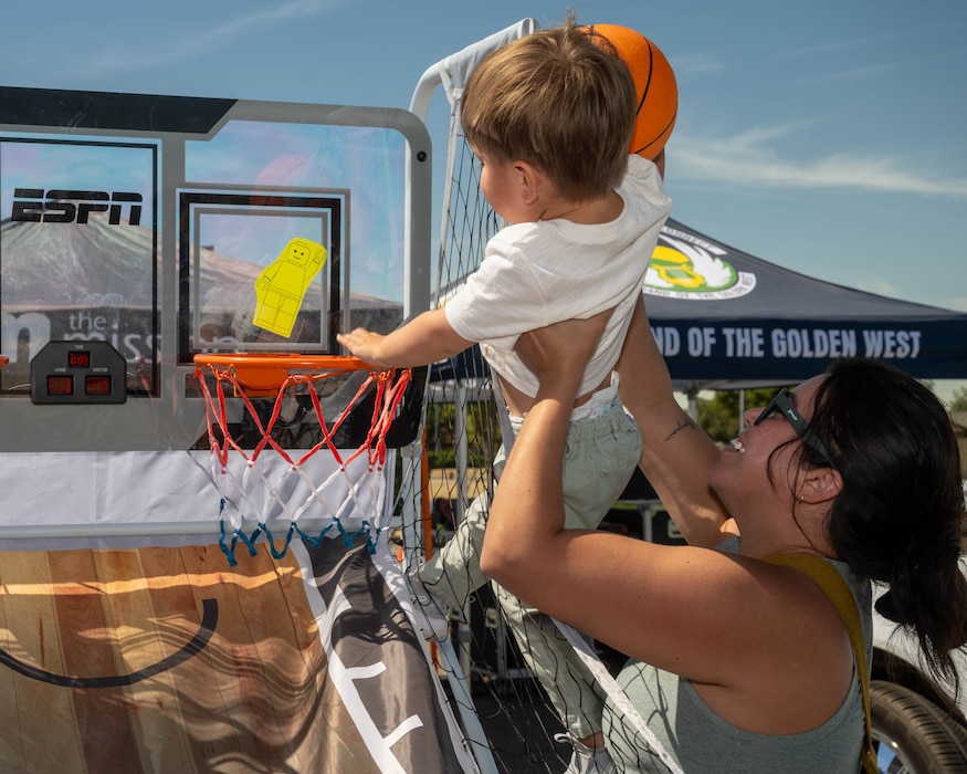 mother lifts toddler to make basketball goal