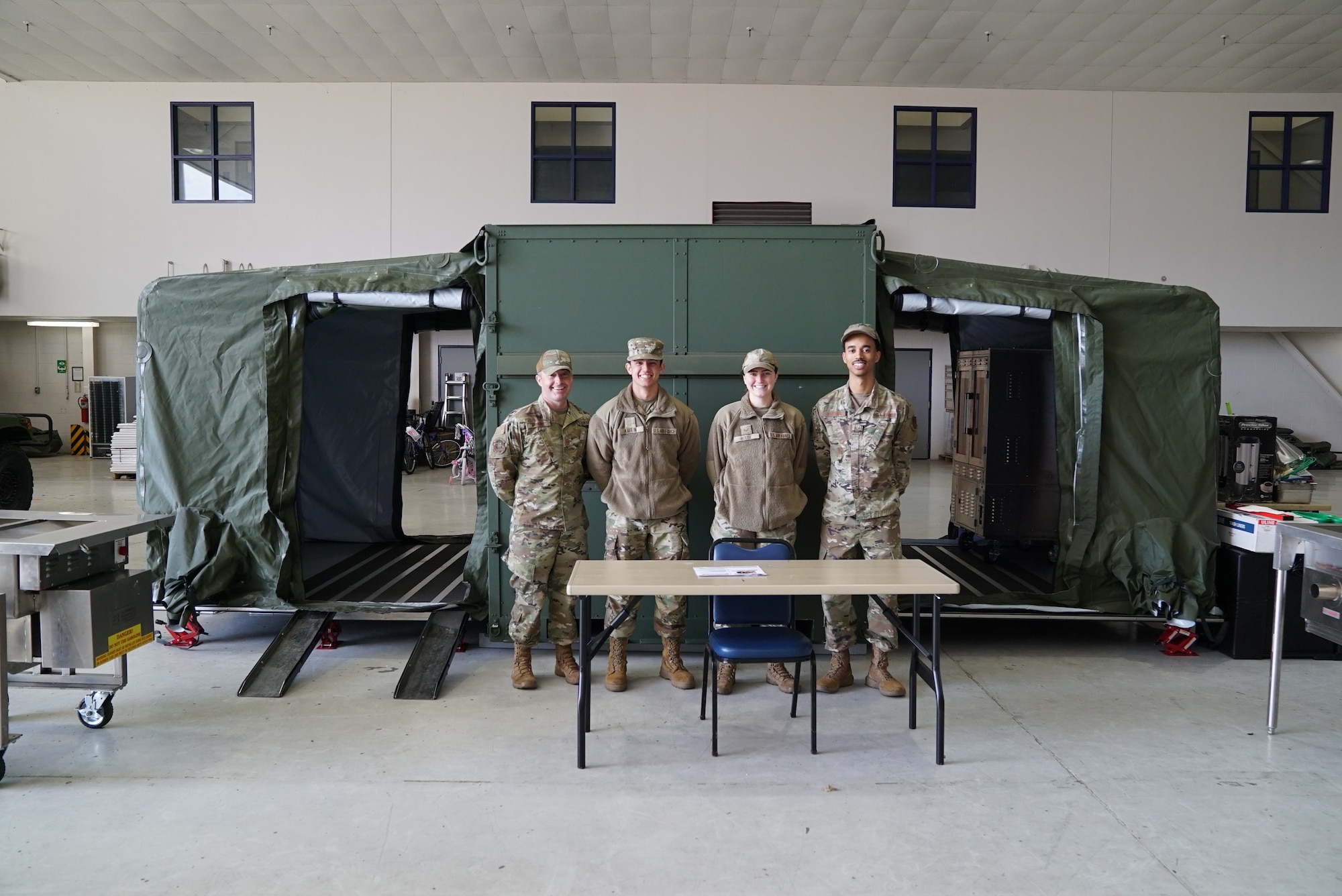 178th Wing members pose in front of a mobile popup kitchen, during the 2025 Springfield Air National Guard Base Community Day, on base in Springfield, Ohio, April 10, 2025. The wing invited local community leaders to participate in many briefings on the wing’s capabilities, a base tour, and an equipment display.  (U.S. Air National Guard photo by Staff. Sgt. Jillian Maynus)
