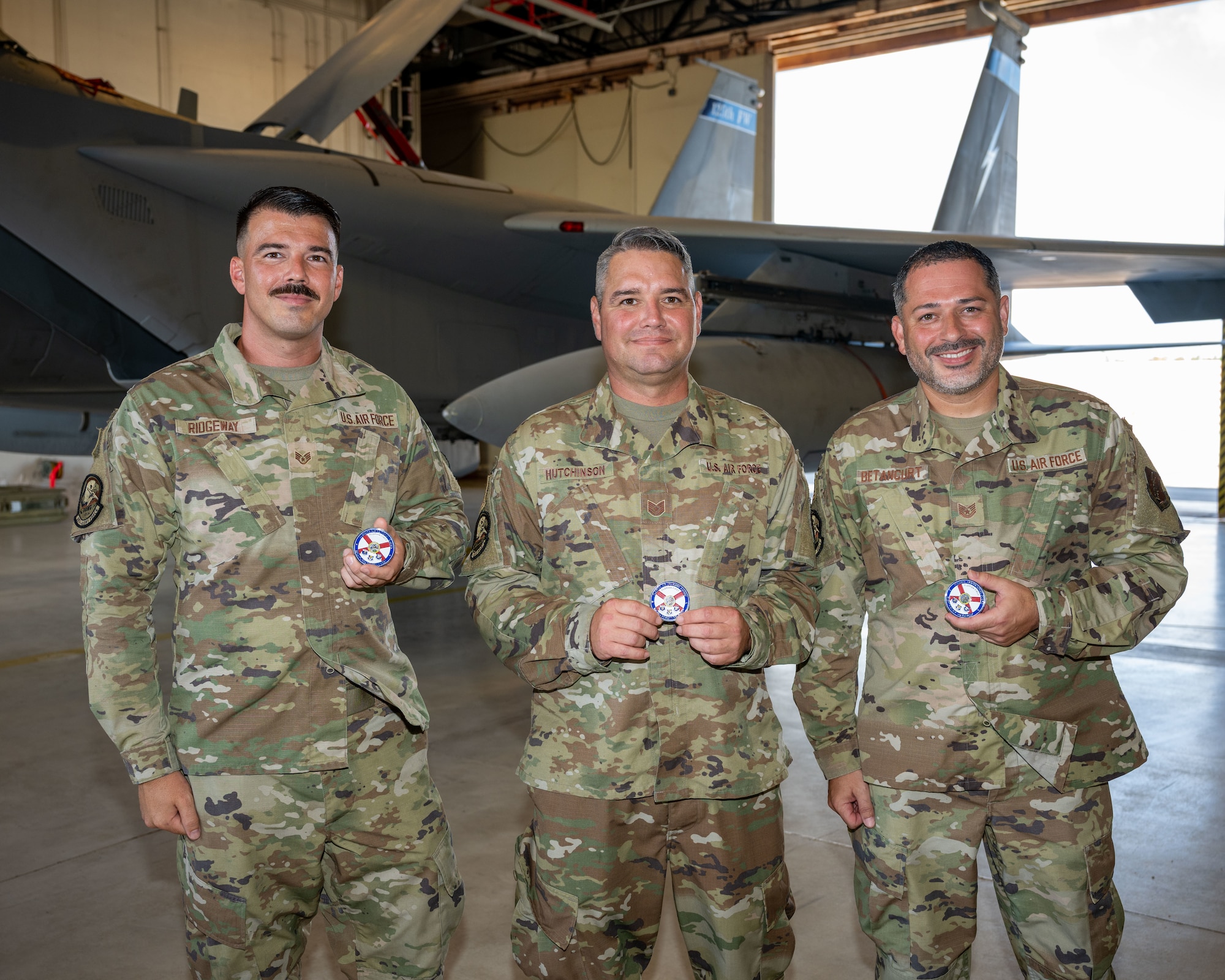 Staff Sgt. Tyler Ridgeway, Tech. Sgt. Michael Hutchinson, and Tech. Sgt. Angelo Betancurt, all with the 125th Fighter Wing’s Detachment 1, display challenge coins presented by Brig. Gen. Richard L. Coffey III, Assistant Adjutant General (Air) for the Florida Air National Guard, at Homestead Air Reserve Base, Florida, Aug. 11, 2025.