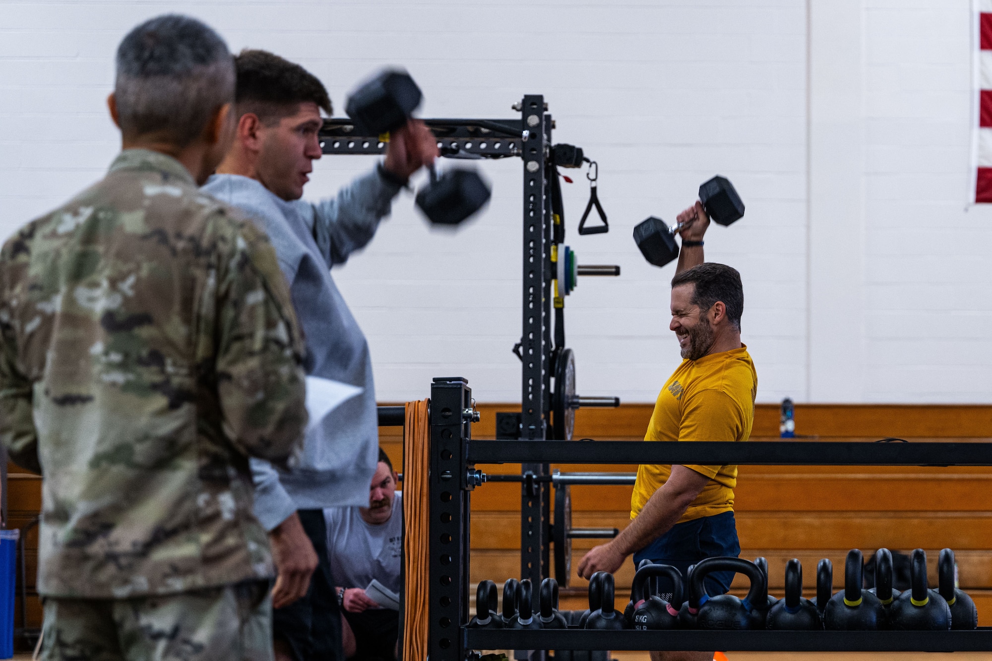 Military members in physical training gear performs a physical challenge.