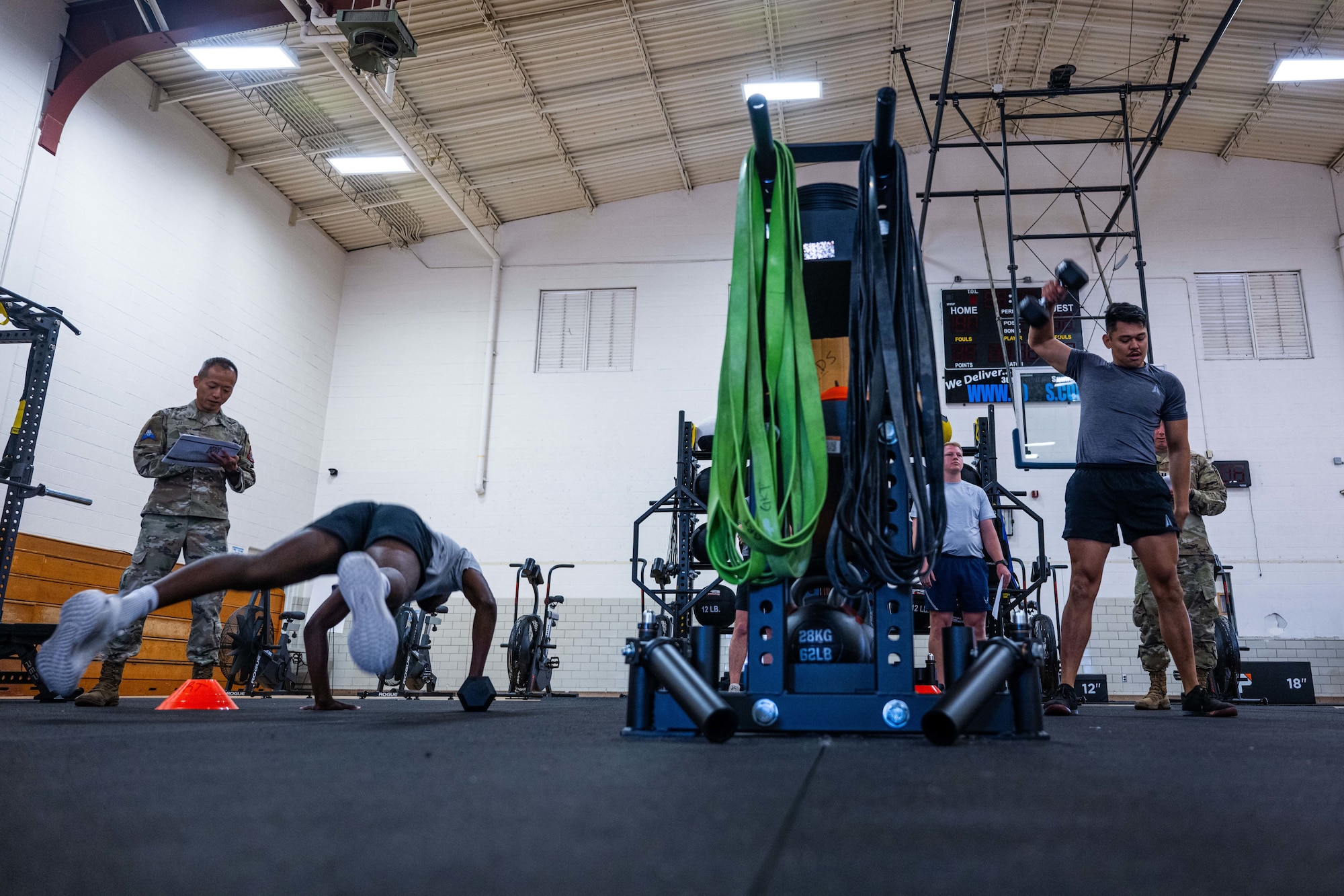 Military members in physical training gear performs a physical challenge.