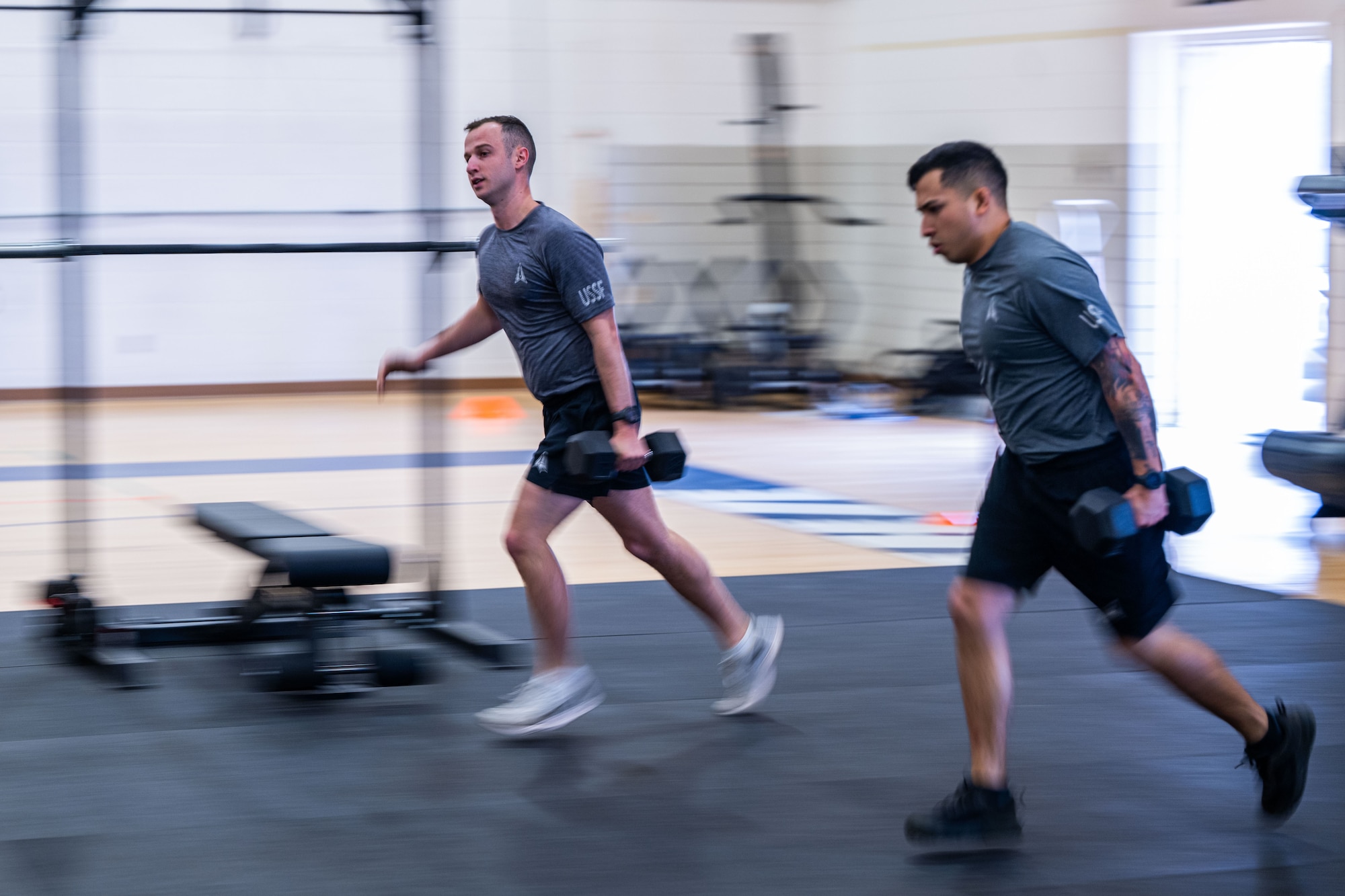 Military members in physical training gear performs a physical challenge.