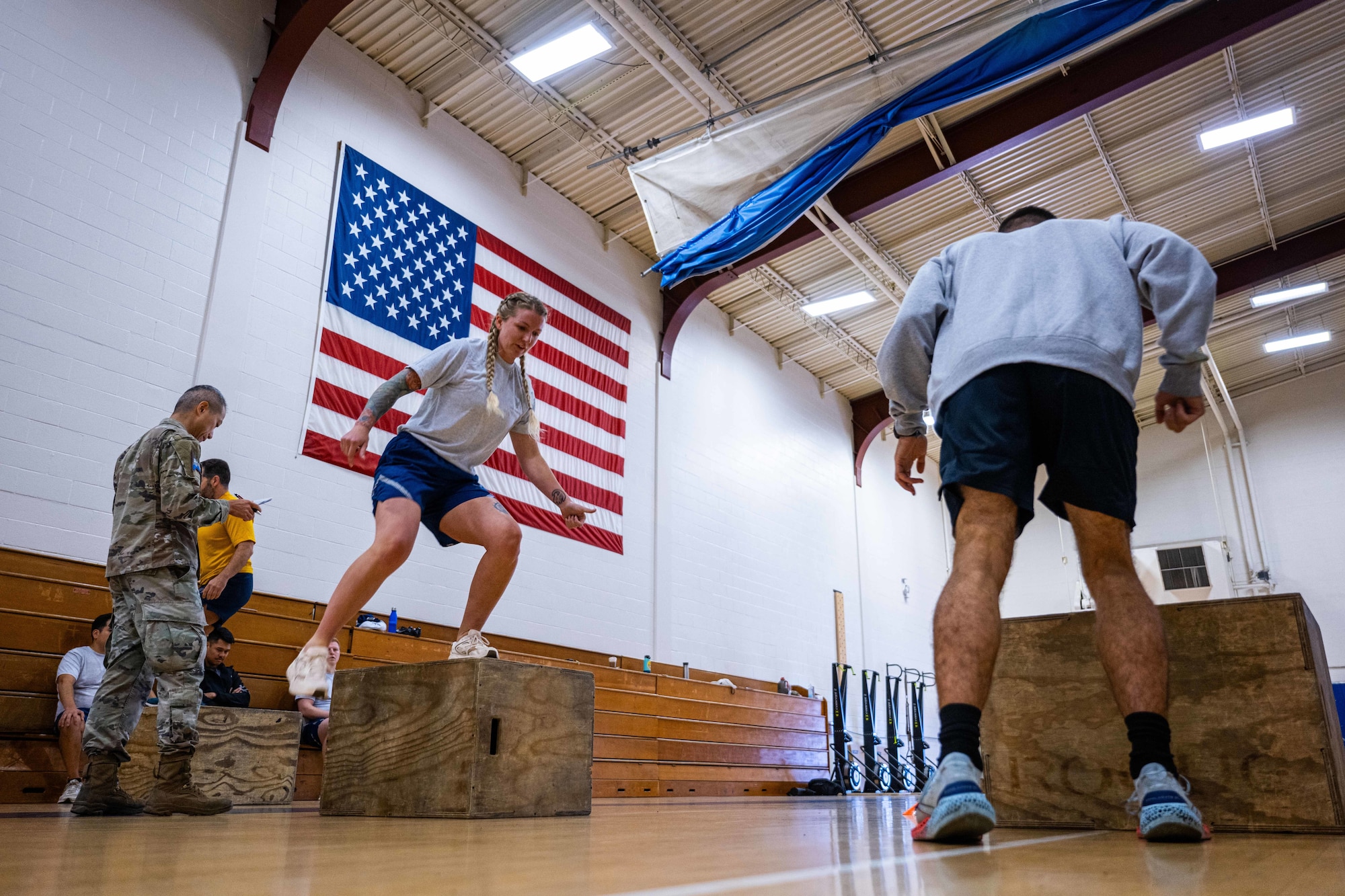Military members in physical training gear performs a physical challenge.