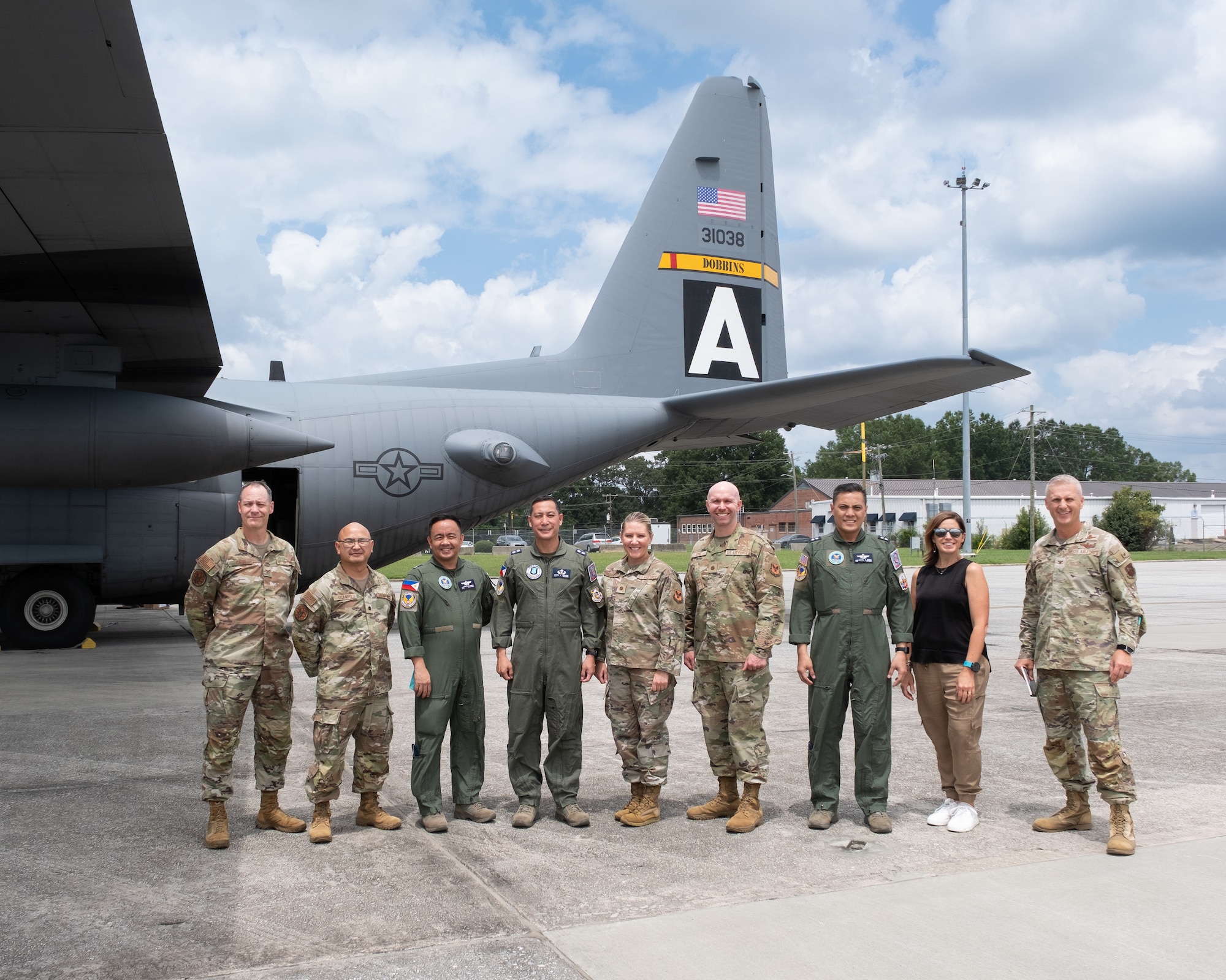 people standing in line posing for photo in front of aircraft