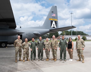 people standing in line posing for photo in front of aircraft