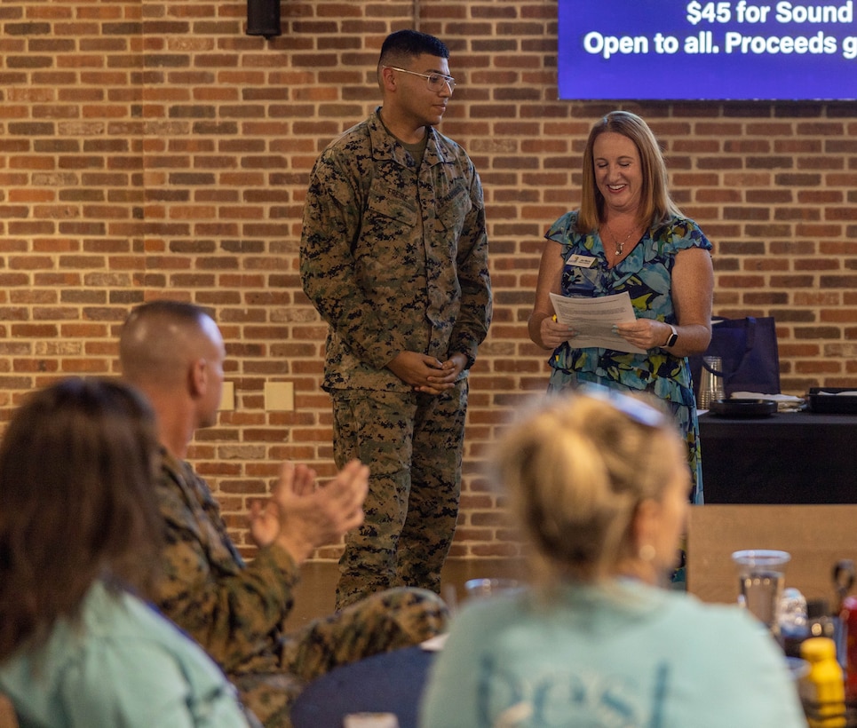 U.S. Marine Corps Lance Cpl. Matthew Freire, left, an aircraft avionics technician, assigned to Marine Fighter Attack Squadron 542, Marine Aircraft Group 14, 2nd Marine Aircraft Wing is awarded Service Person of the Quarter for Carteret County and Jennifer Merlo, a chairperson with the Carteret County Chamber of Commerce Military Affairs Committee reads off his achievements during a ceremony at the Cherry Point Public House, Marine Corps Air Station Cherry Point, North Carolina, Feb. 26, 2025.